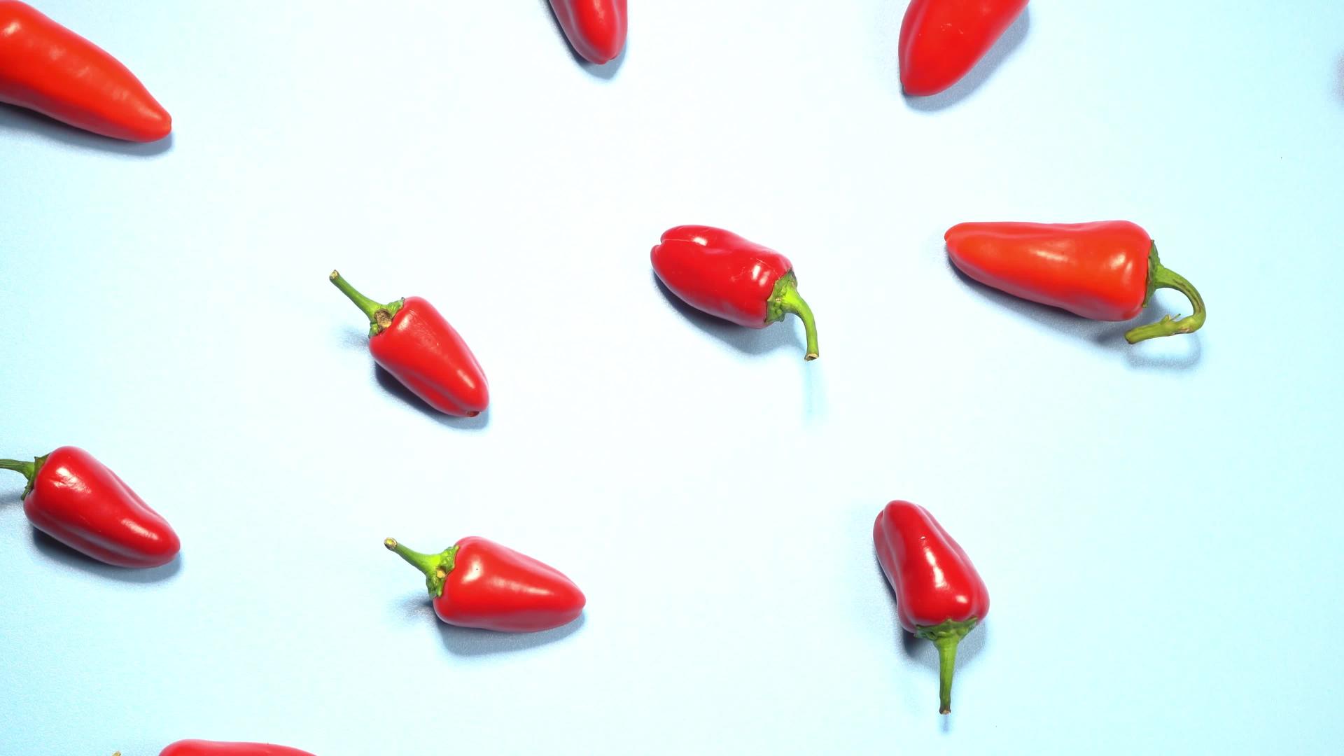 小红辣椒的顶视图混乱地散落在蓝色背景上视频的预览图