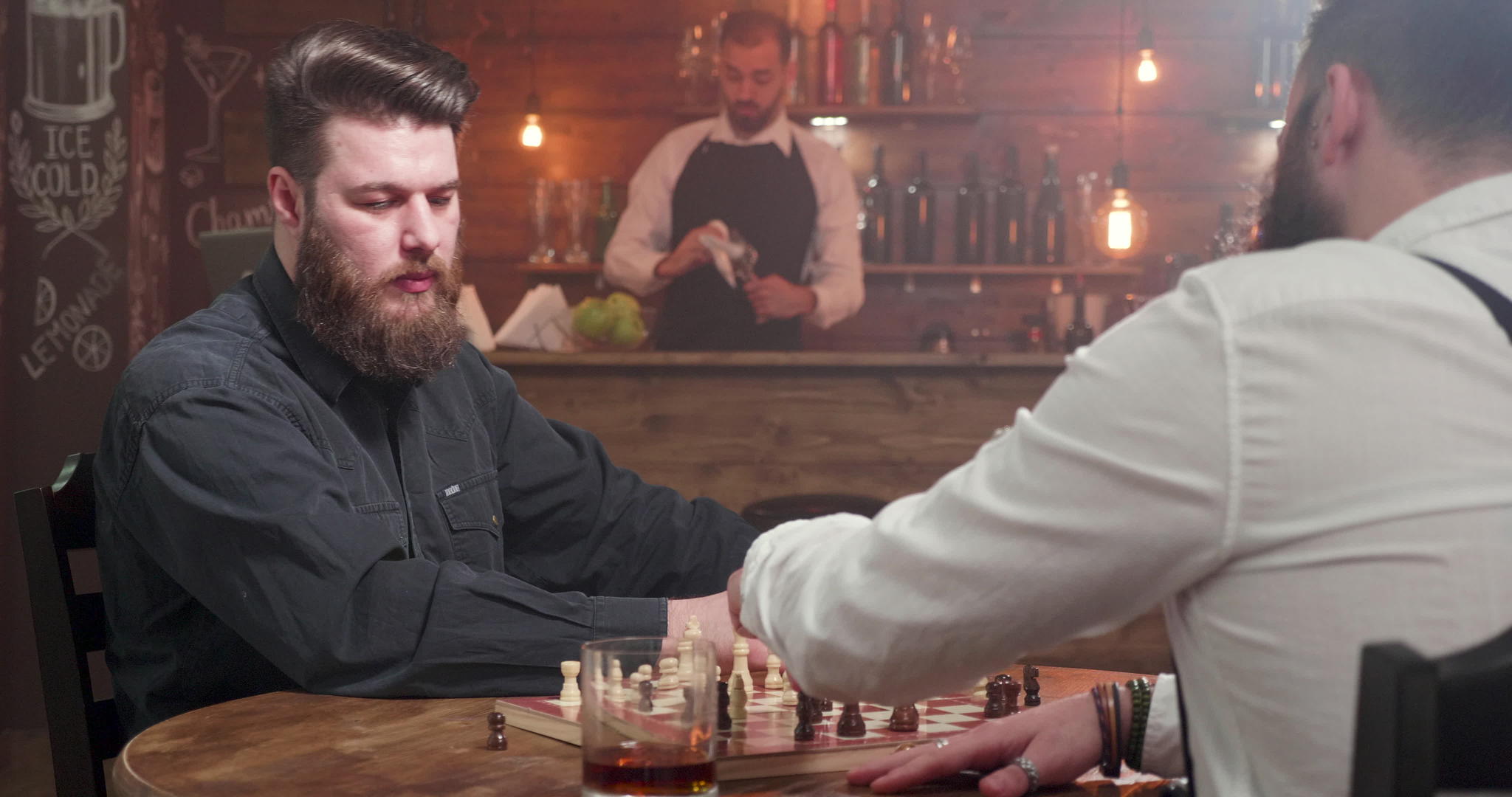 两个时髦的嬉皮士男子在酒吧里玩象棋游戏视频的预览图