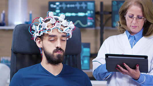 男性男性患者在医生检查大脑活动时闭上眼睛；检查脑活动视频的预览图