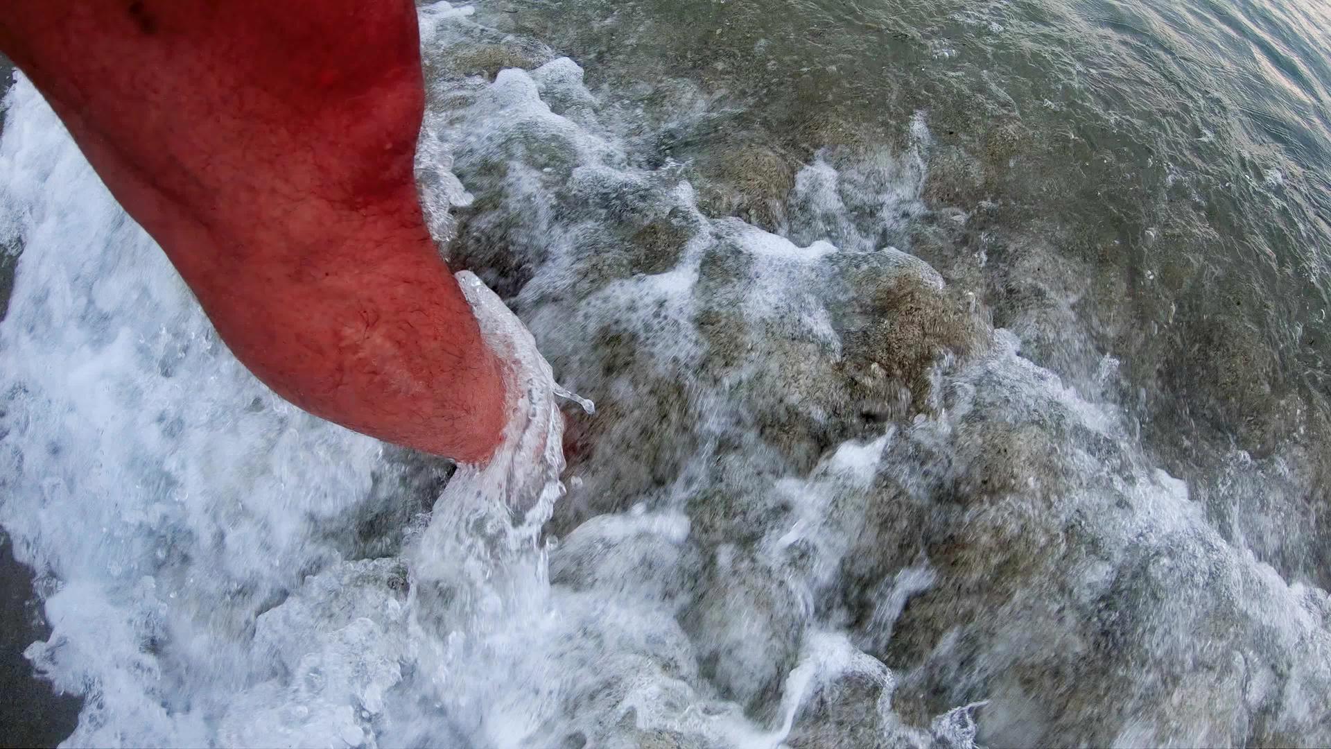 男人用脚在海里清新海浪在海岸上缓慢移动视频的预览图