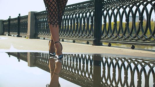 穿着高跟鞋的女人的腿在水坑里行走视频的预览图