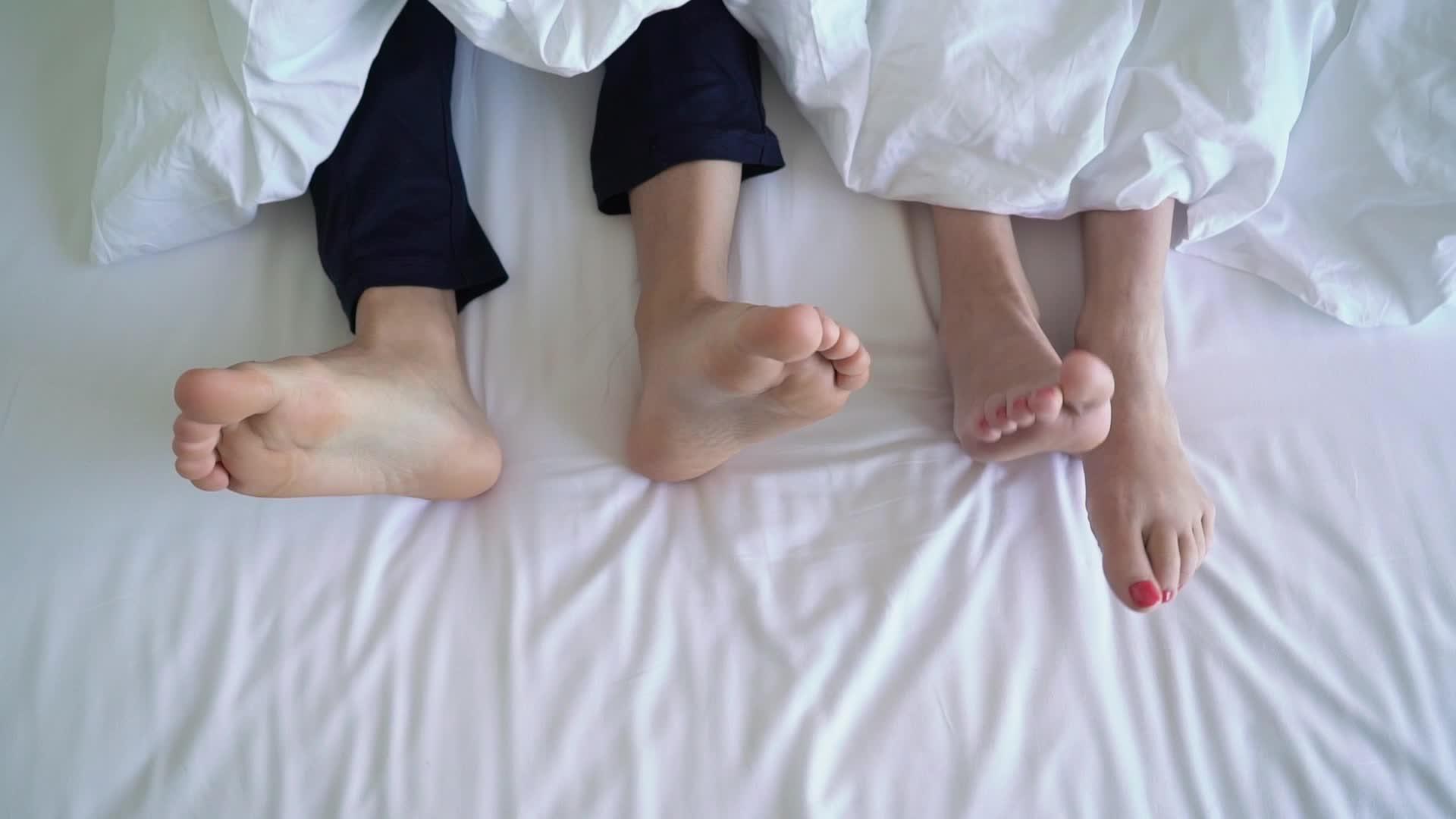床上的年轻夫妇双腿放在床椅下面视频的预览图