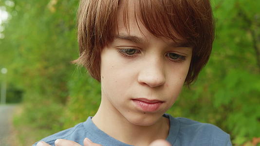 年轻男孩的肖像男孩的脸和眼睛都闭着青春树的背景视频的预览图