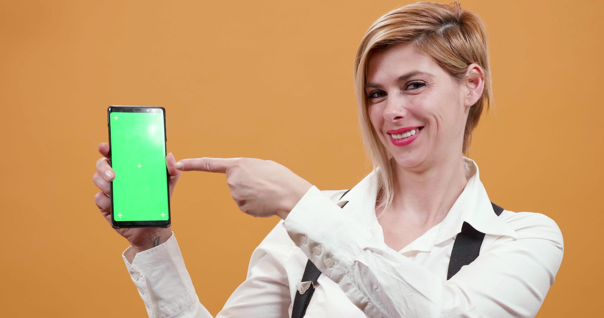 女人用手指指着智能手机上面有一个绿屏视频的预览图