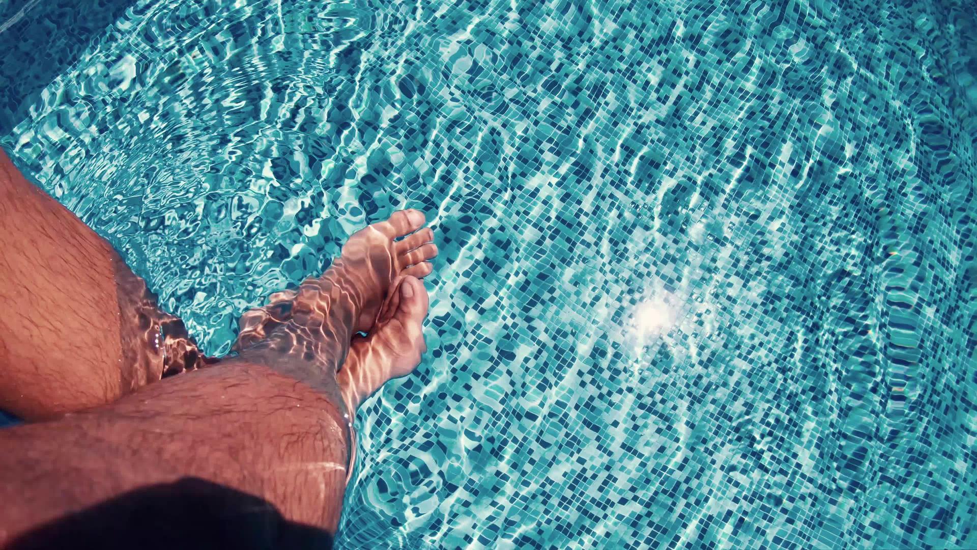 坐在游泳池边双腿在水中摇摆视频的预览图