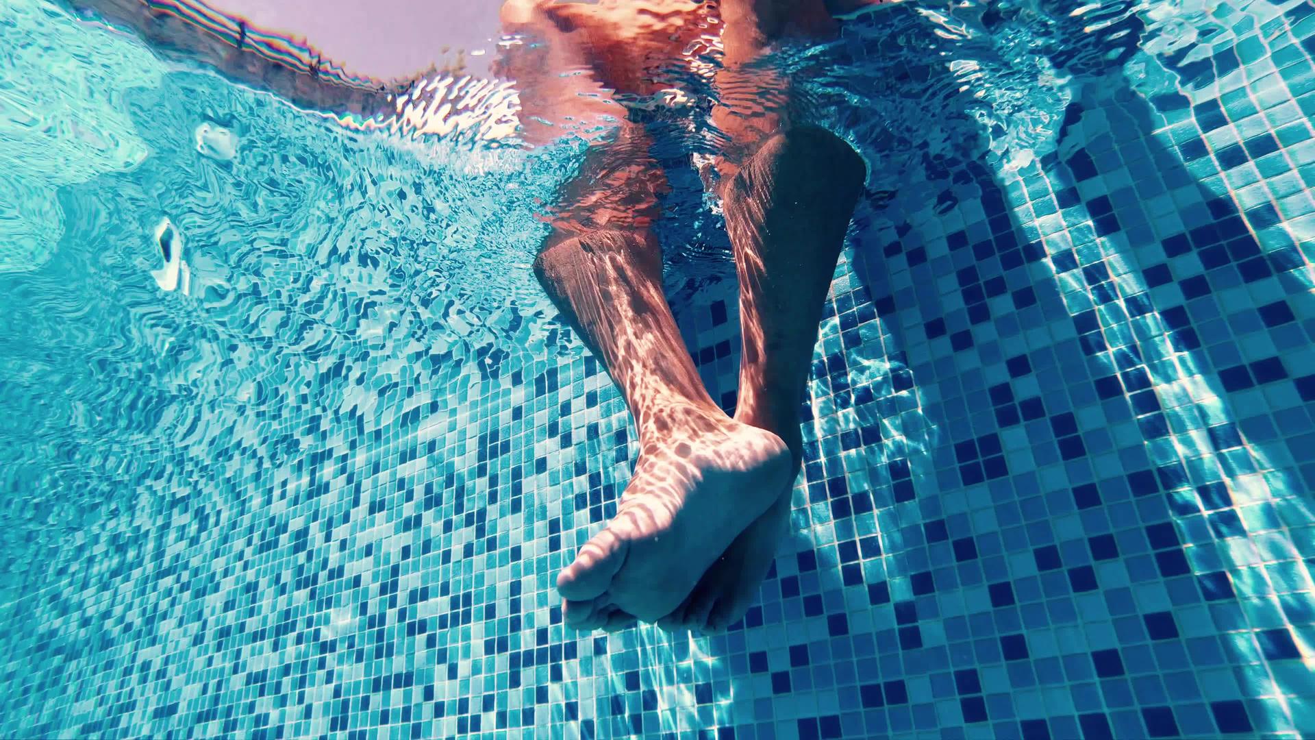 在游泳池里放松的腿看着水下男人的眼睛视频的预览图