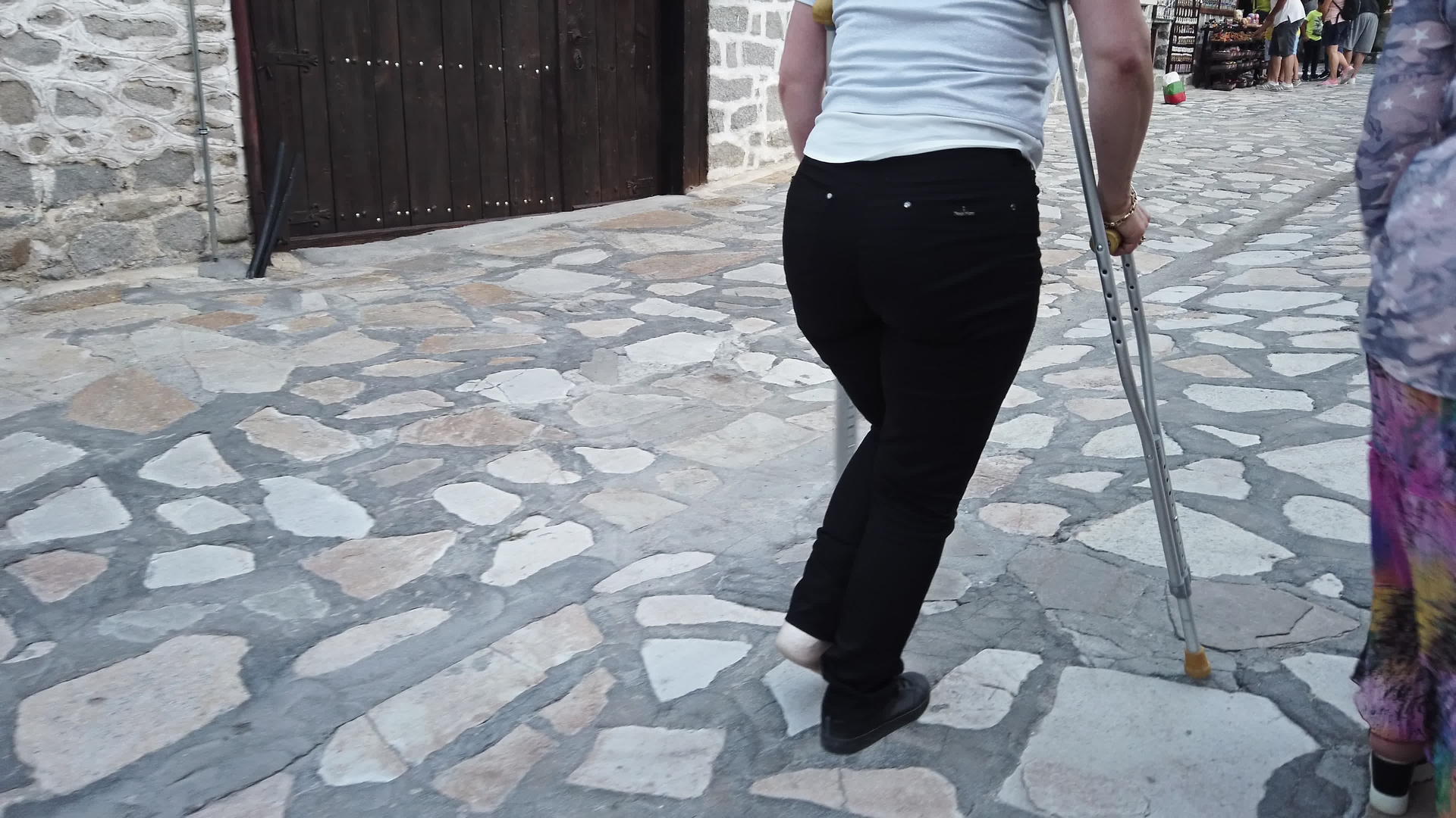 妇女在人行道上拄着拐杖走路视频的预览图