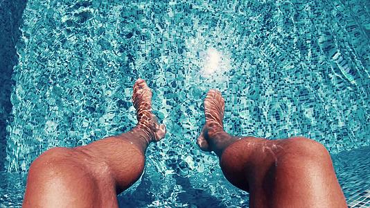 男人在豪华的游泳池里打扫和摇摆他的腿视频的预览图