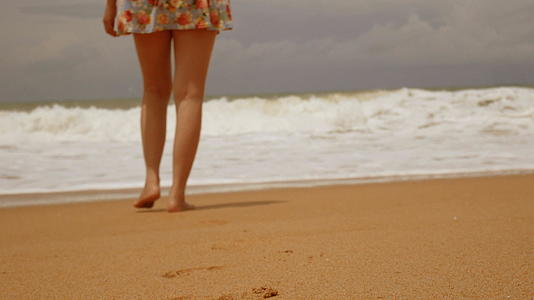 赤脚走在湿沙岛海滩上的年轻女孩在夏天有大浪视频的预览图