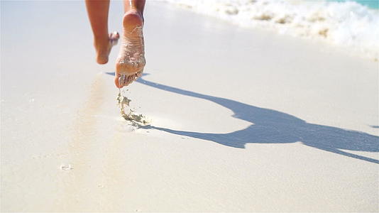 在浅水的白色沙滩上跑来跑去度假和赤脚的概念慢动作视频的预览图