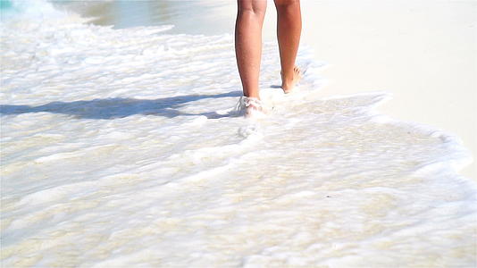 在浅水的白色沙滩上跑来跑去度假和赤脚的概念慢动作视频的预览图