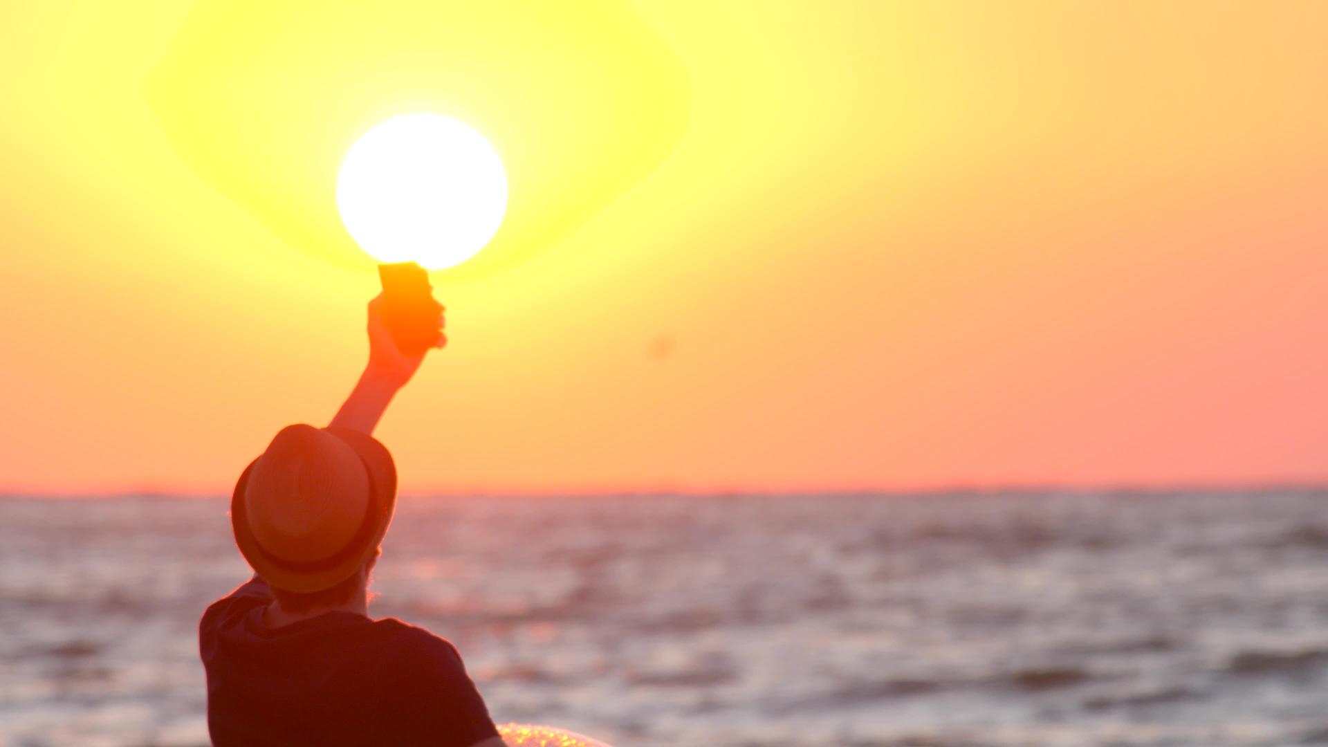 男人在海上自拍帅哥在日出时拍手机照片视频的预览图
