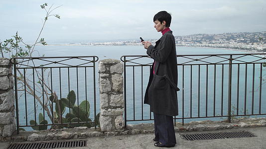 女性在市风海滨使用智能手机应用程序发短信视频的预览图