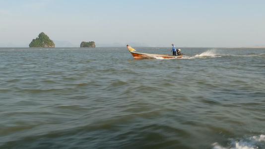 传统的长尾鱼船上的渔民在海浪上漂浮视频的预览图