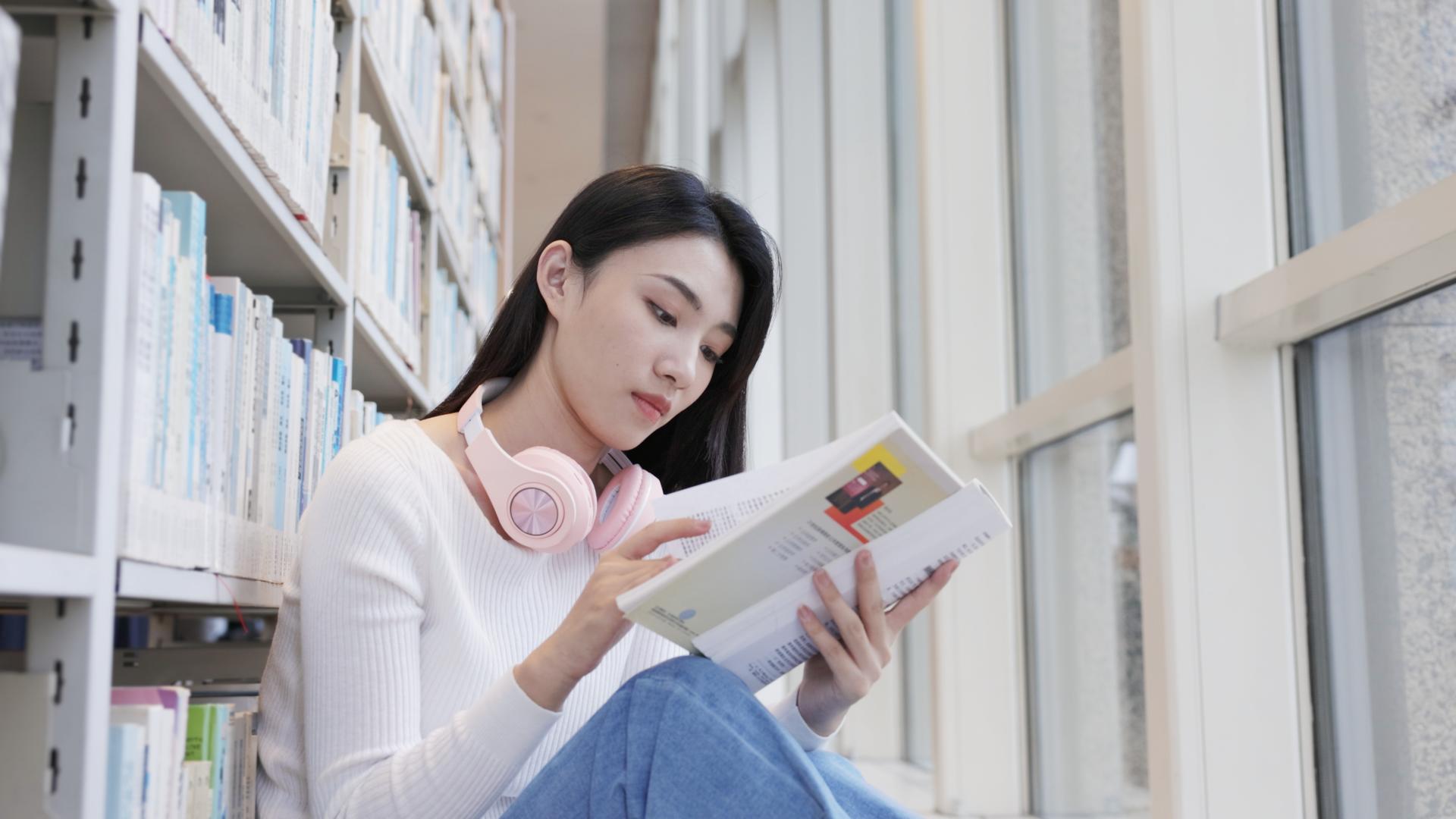 坐在图书馆角落听音乐看书的女大学生视频的预览图
