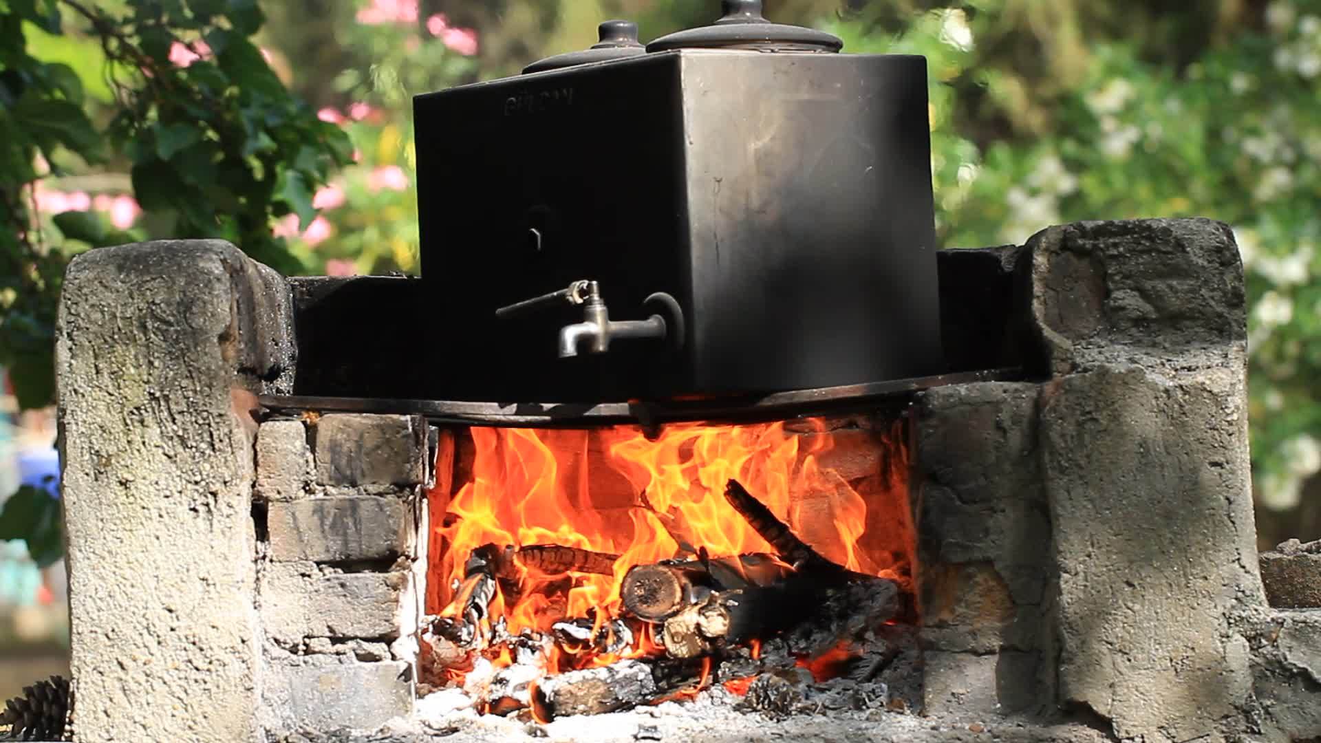 在营火边缘的一个大容器里煮水茶的时间是自然的视频的预览图