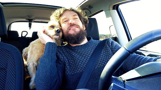 快乐的男人在夏天开车时抱着一只可爱的狗视频的预览图
