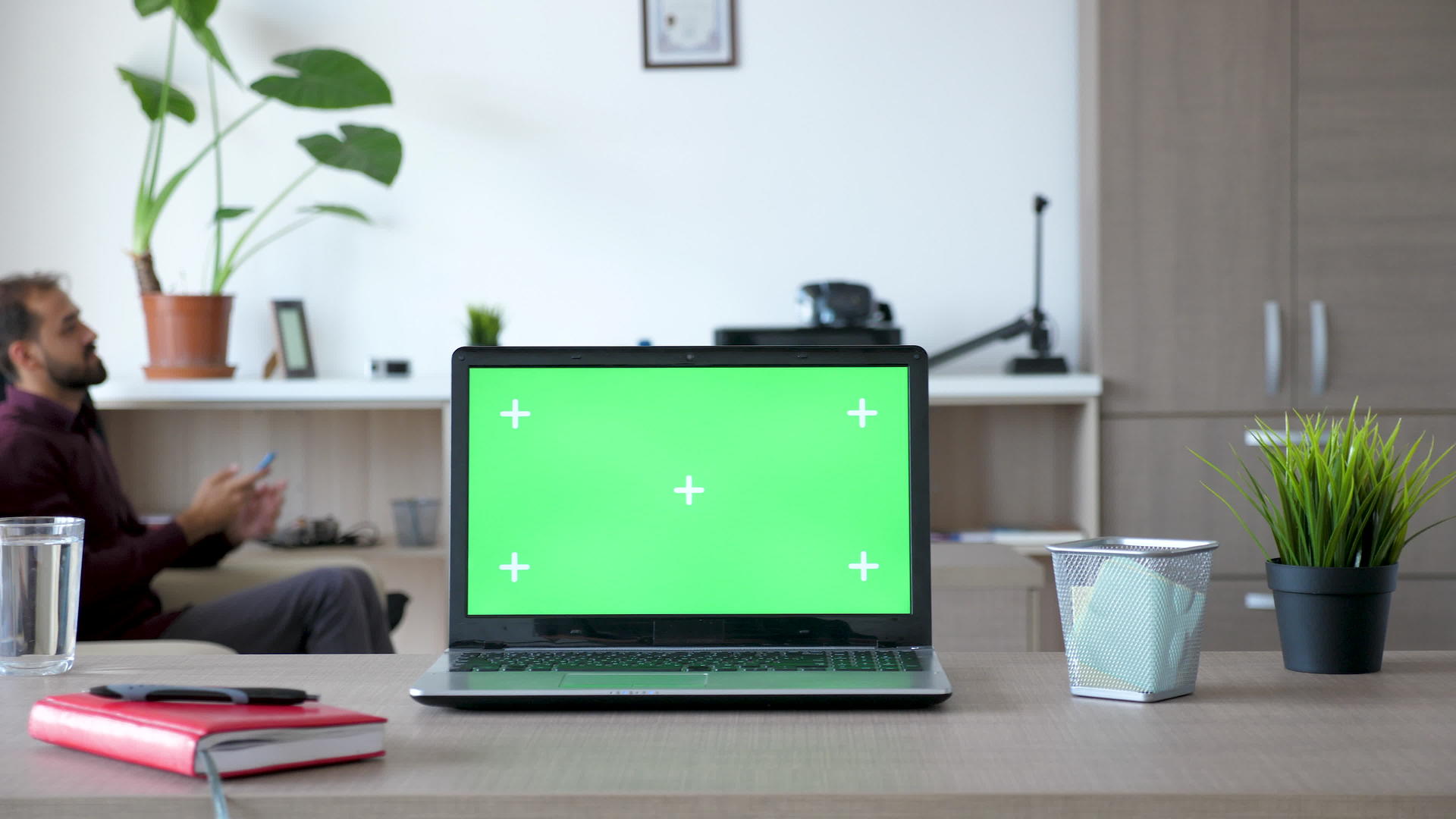 桌子上的笔记本电脑在房子里有一个绿色的屏幕视频的预览图