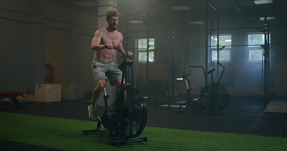 在健身房强壮的男人用机车在健身房做心脏锻炼设备视频的预览图