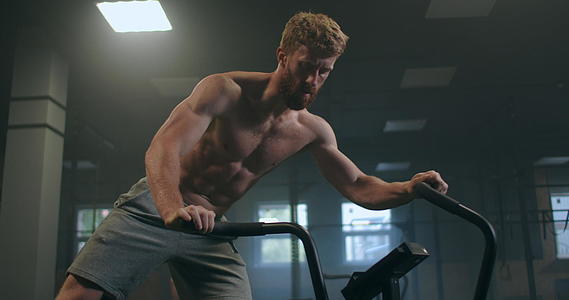 一个男人在健身房以慢动作为主在固定自行车上进行有氧运动视频的预览图