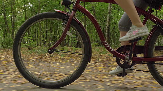 Caucasian女人的腿在公园里踩在自行车上秋天落叶视频的预览图