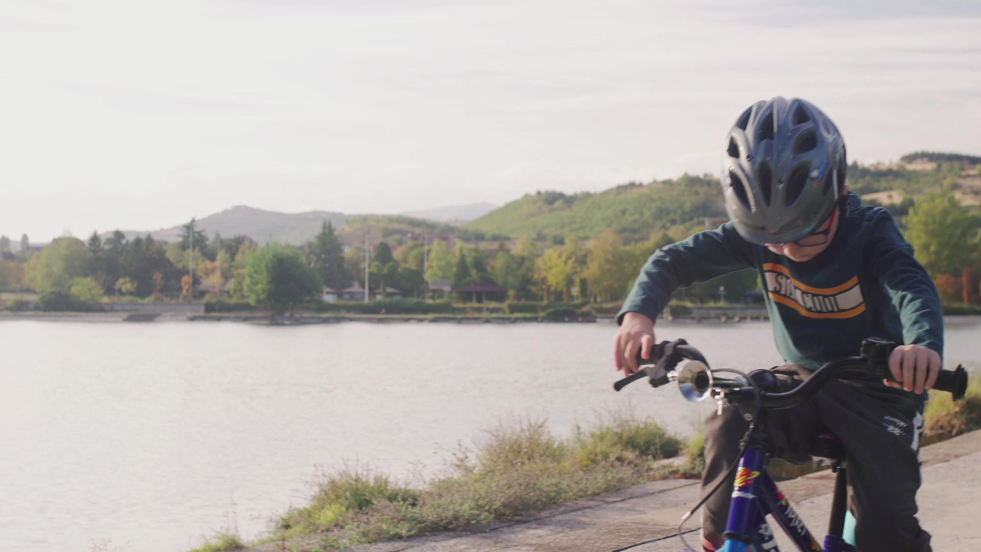 在阳光明媚的秋天孩子们在湖边骑自行车视频的预览图