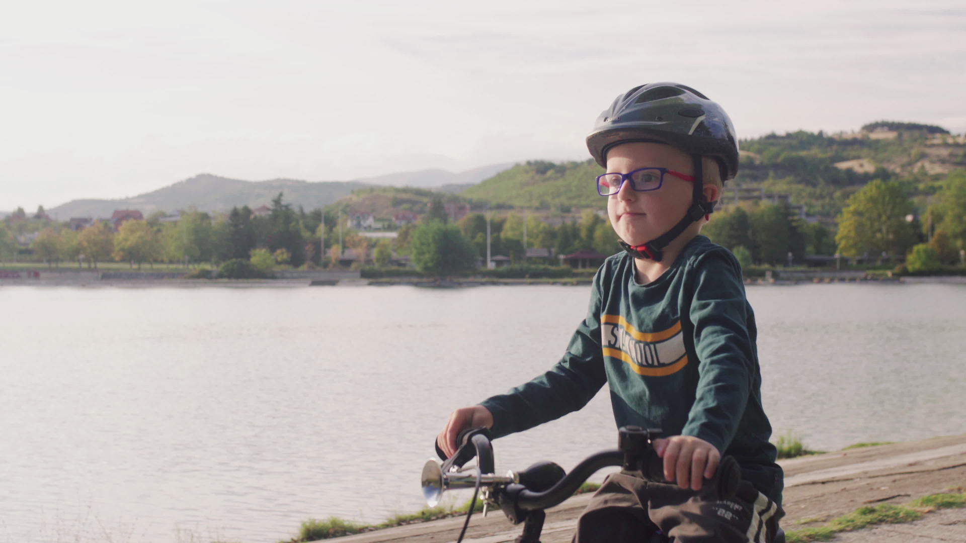 在阳光明媚的秋天孩子们在湖边骑自行车视频的预览图