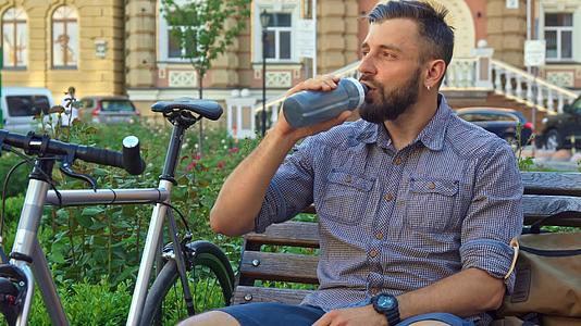 骑自行车的人在长椅上喝水视频的预览图