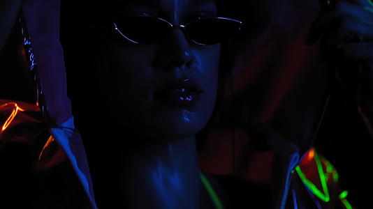 霓虹灯工作室的现代女孩在黑色背景上慢慢移动穿着霓虹灯视频的预览图