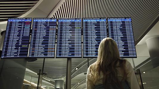 在国际机场查看航班信息板的女性视频的预览图