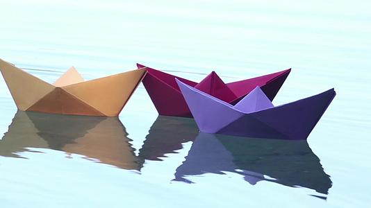 三艘彩色纸船漂浮在水面上视频的预览图