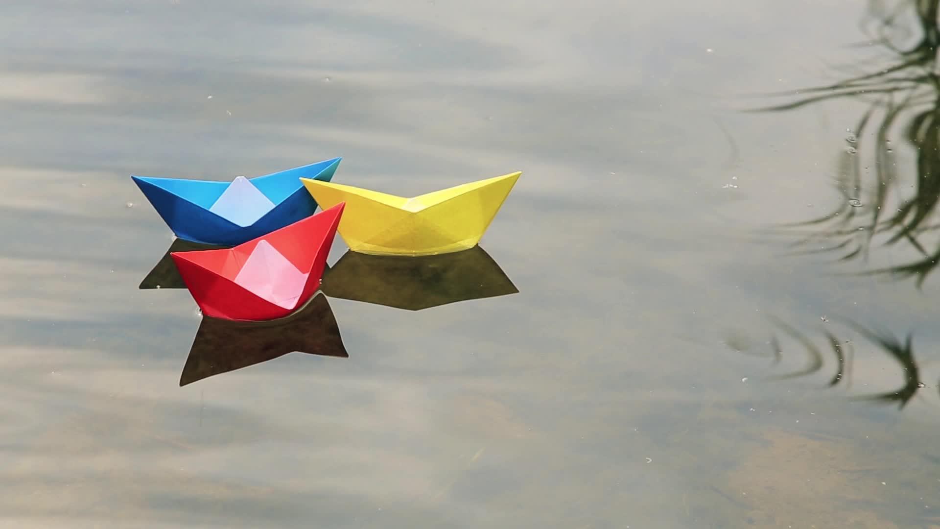 三艘彩色纸船漂浮在水面上视频的预览图