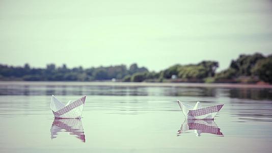 两艘小纸船漂浮在水面上视频的预览图