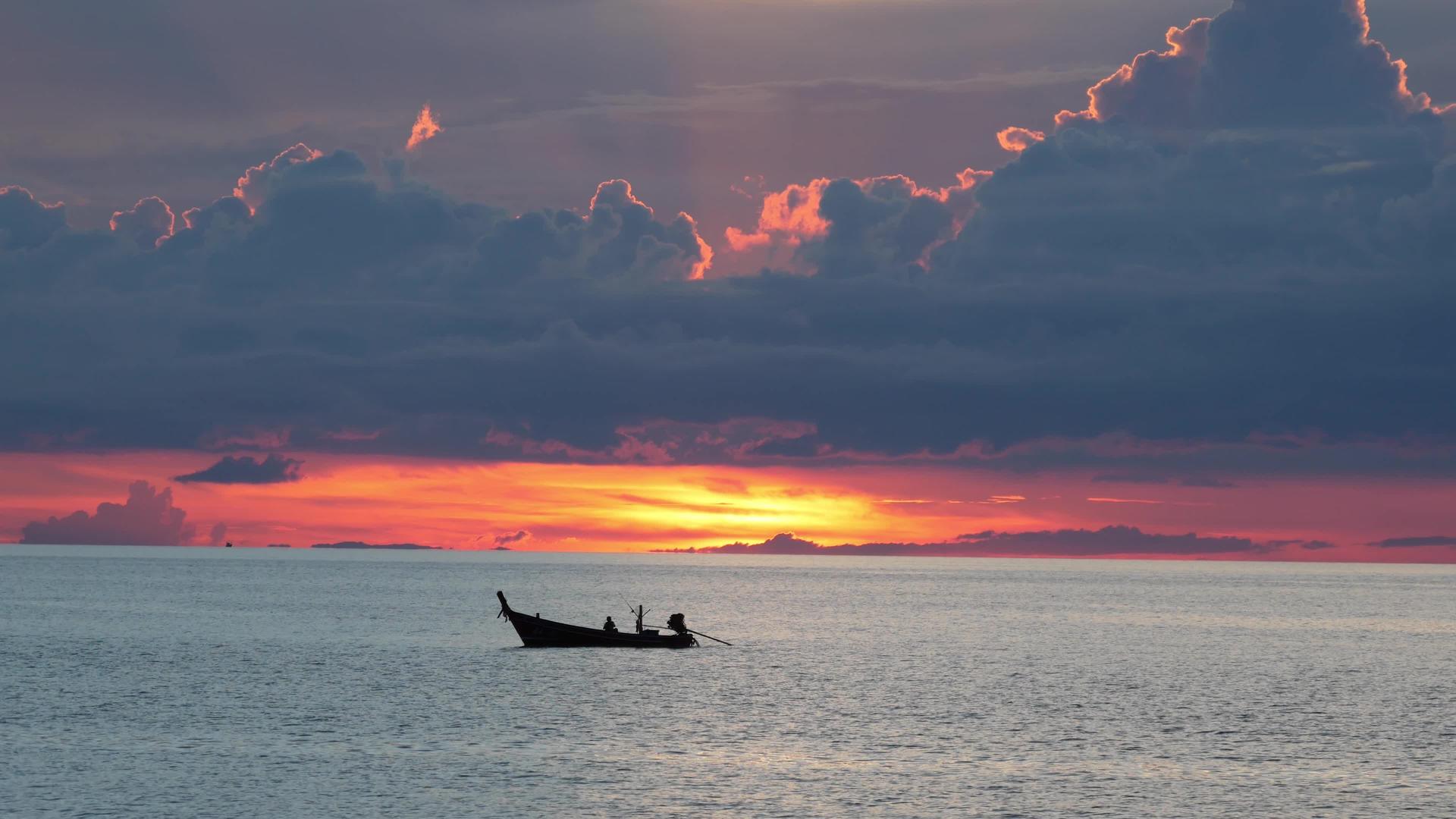 日落时在海上划船日落时在多云的傍晚漂浮在平静的海面上视频的预览图
