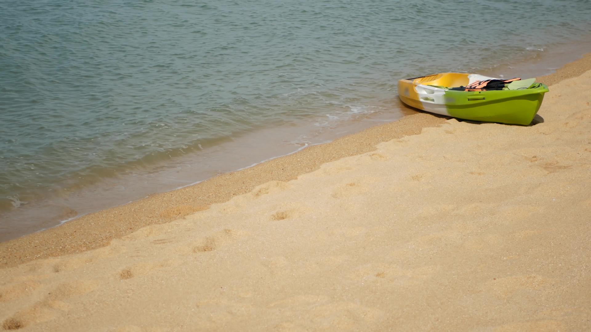 用桨划在沙滩上的皮划艇被蓝色的海浪冲走了视频的预览图