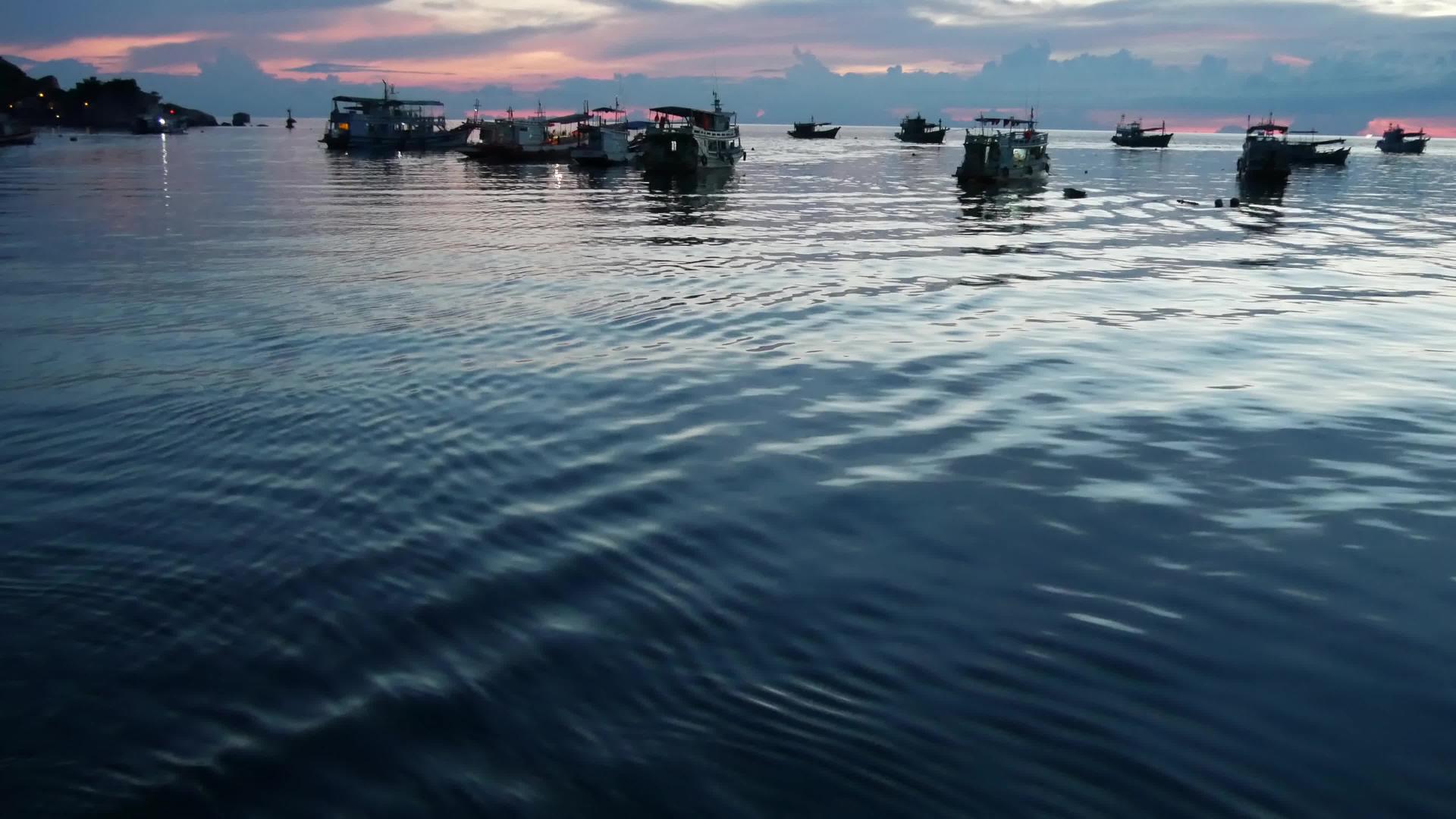 日落时漂浮在港口海面上的小船泰国海洋表面视频的预览图