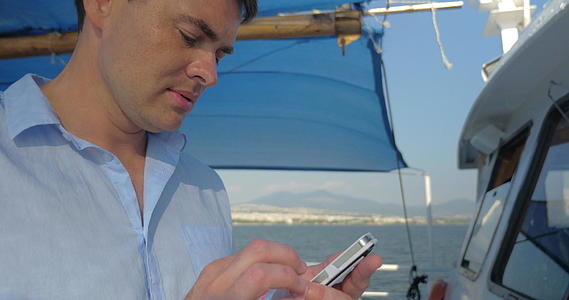 那个人正在打他的智能手机而他在夏天阳光明媚的日子在船上视频的预览图