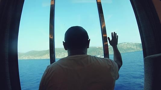 游客从豪华船舱窗的风景中观看海岸旅游度假视频的预览图