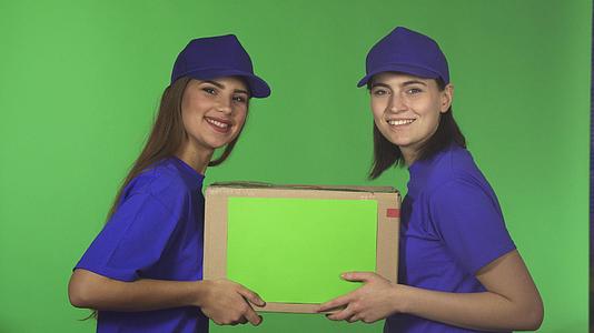 两个快乐的女服务员微笑着用纸板包装视频的预览图