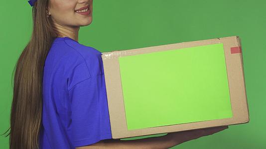 一名微笑的女送货员拿着一个纸箱被拍到后视镜视频的预览图
