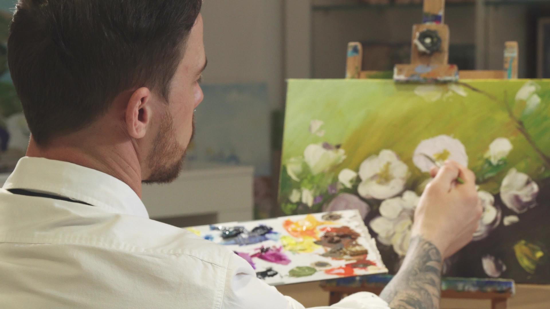 一位男性艺术家在艺术工作室画画时的后视镜头视频的预览图