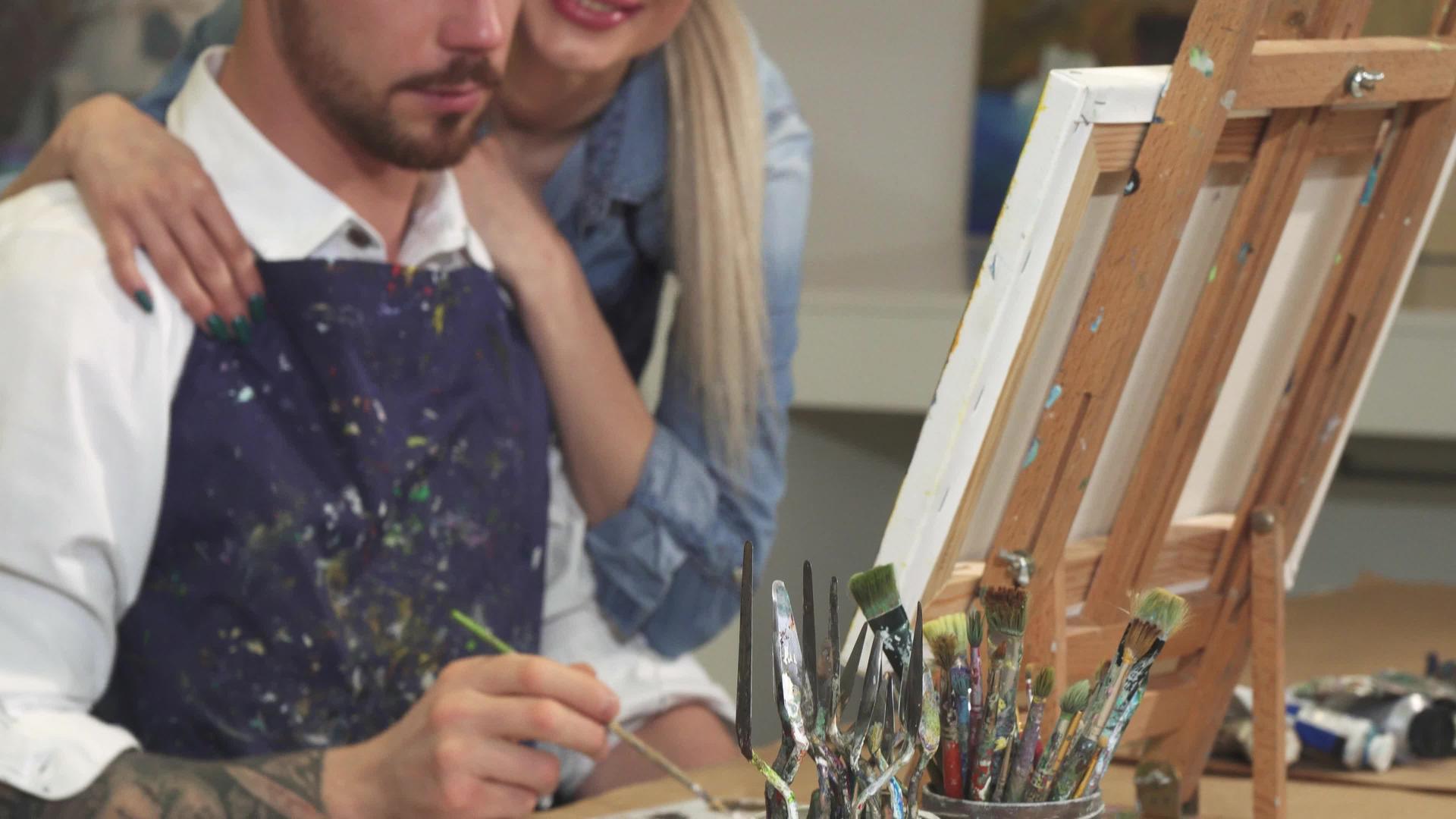 一位专业的艺术家在画上画了他的女朋友拥抱他的画视频的预览图