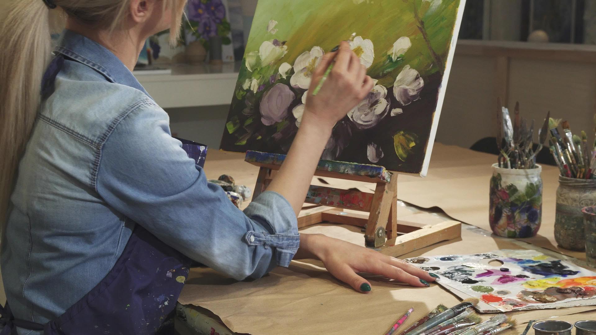 一位微笑的女艺术家在她的艺术工作室画花视频的预览图
