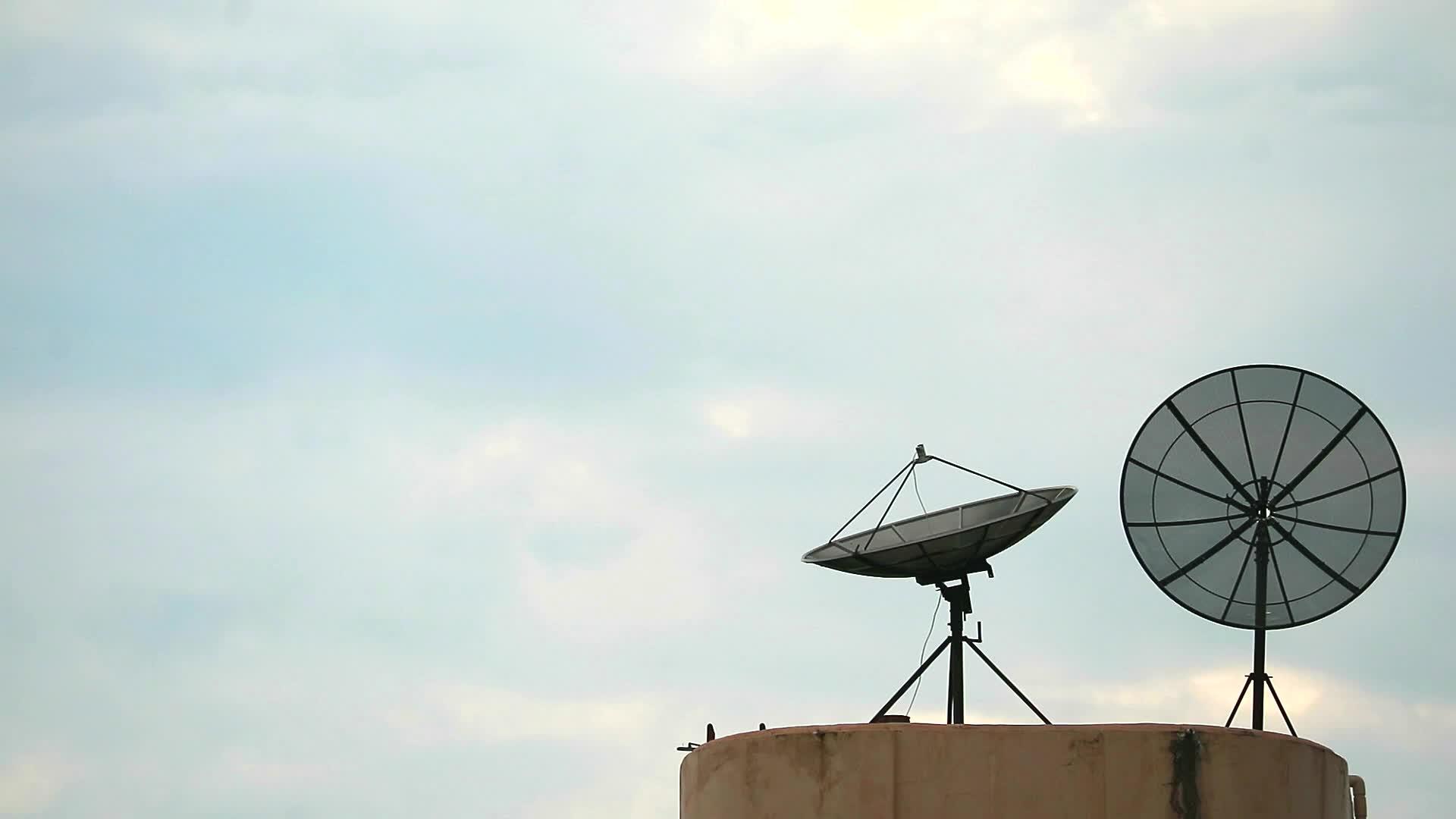 鸟儿飞来挂在两颗卫星天线的晨空背景上视频的预览图