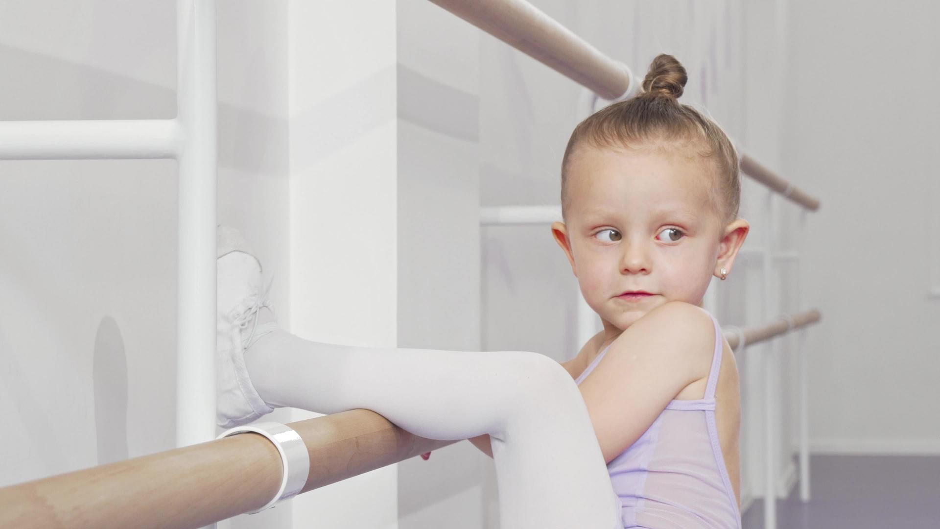 可爱的芭蕾舞小女孩把腿放在芭蕾舞吧上伸展起来视频的预览图