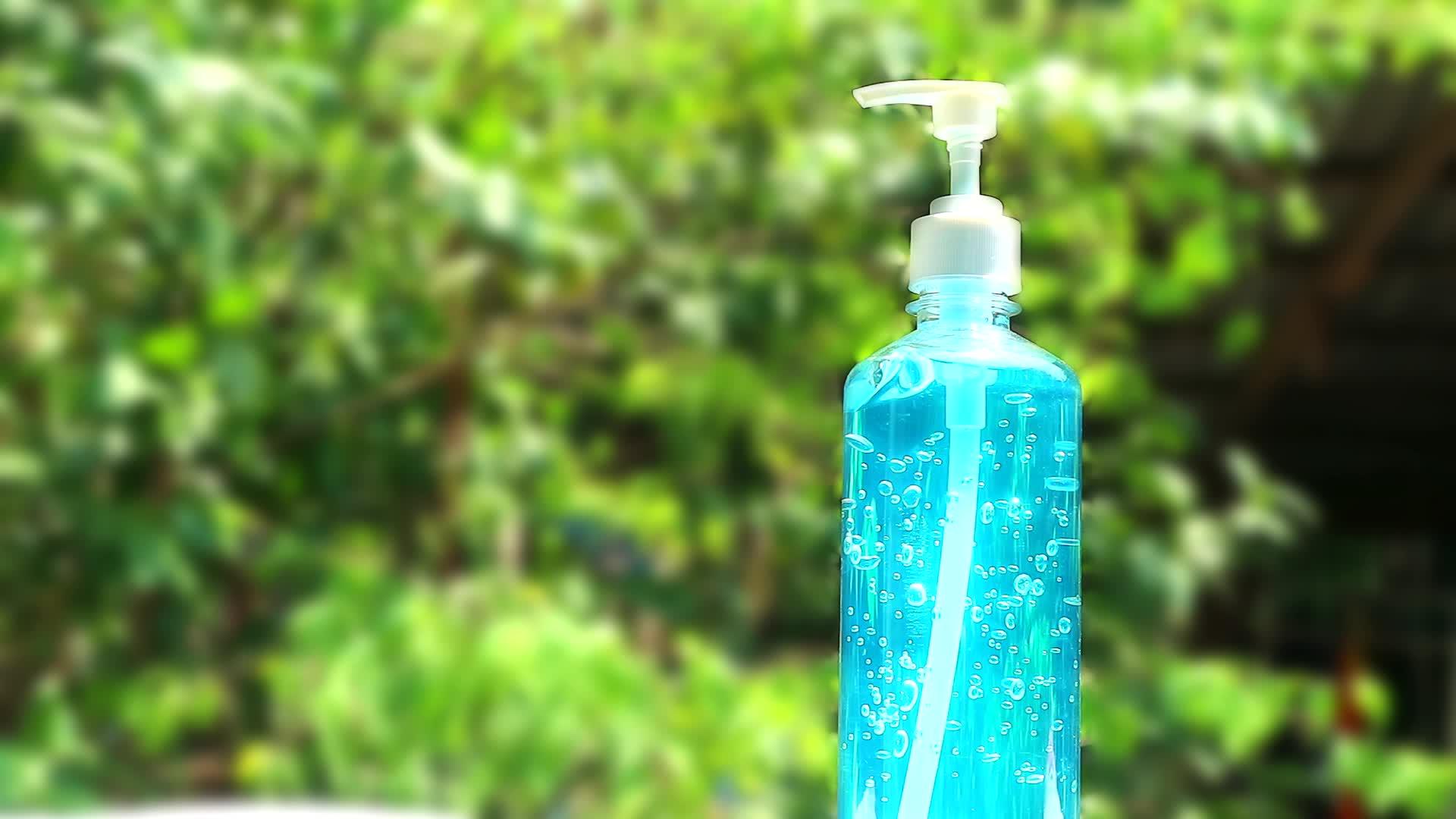 花园里的蓝色凝胶瓶和模糊的绿树视频的预览图