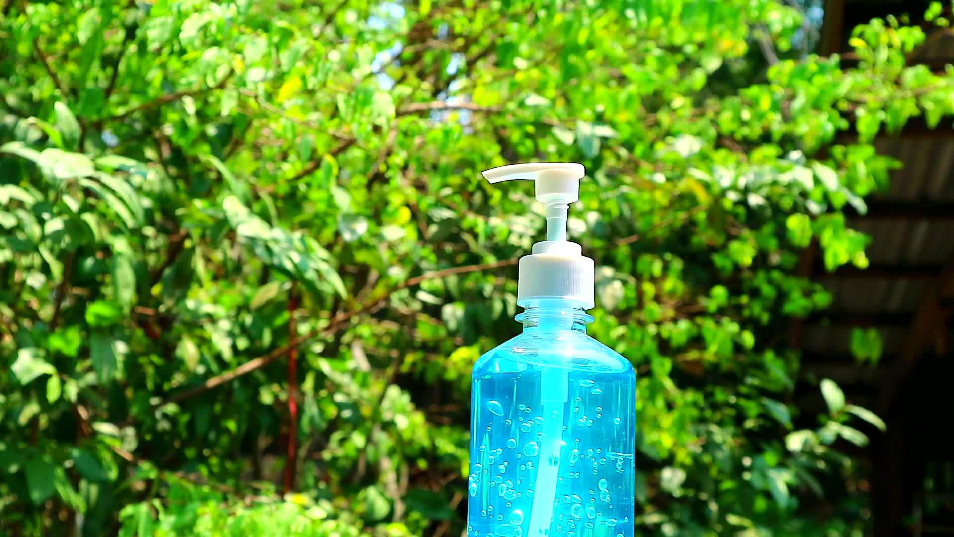 蓝色凝胶瓶和模糊的绿树慢慢地穿过花园视频的预览图