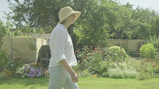 高级女老人在花园里走过自己的花园视频的预览图