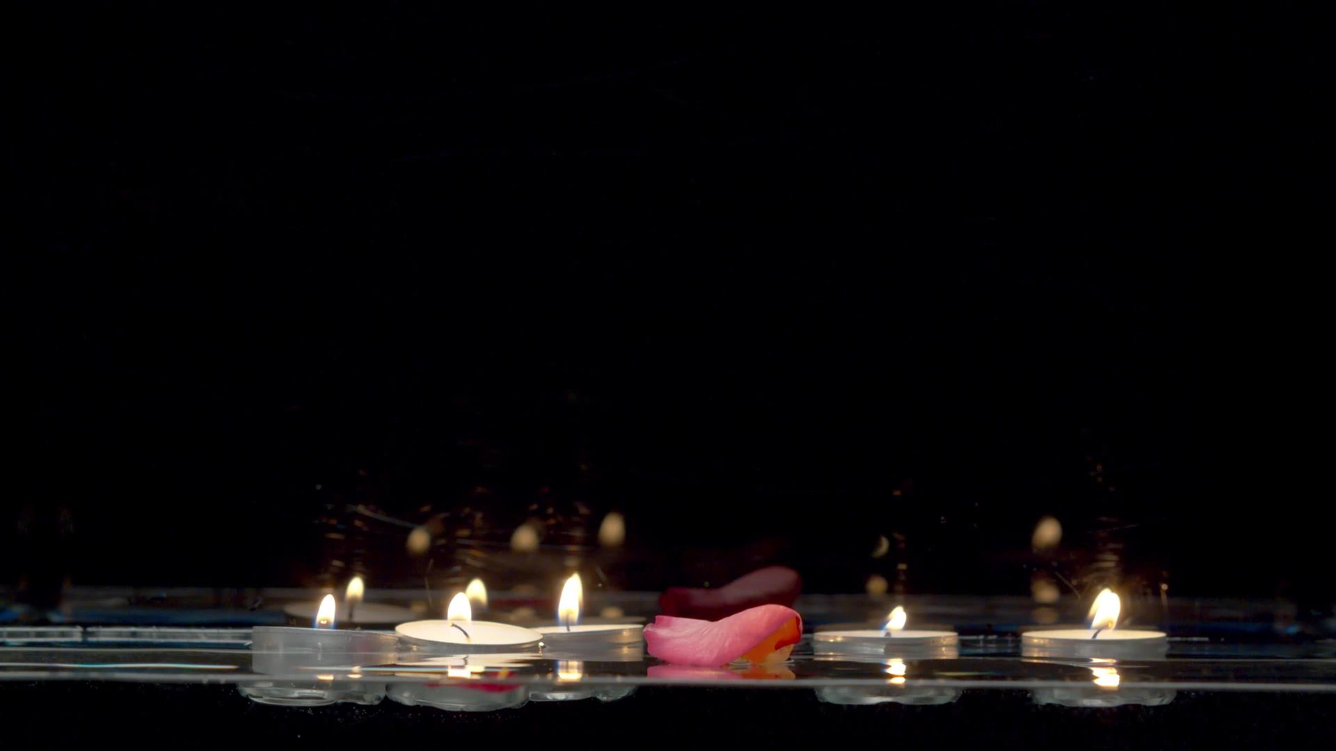 漂浮在水面上的蜡烛和落下的玫瑰花瓣视频的预览图