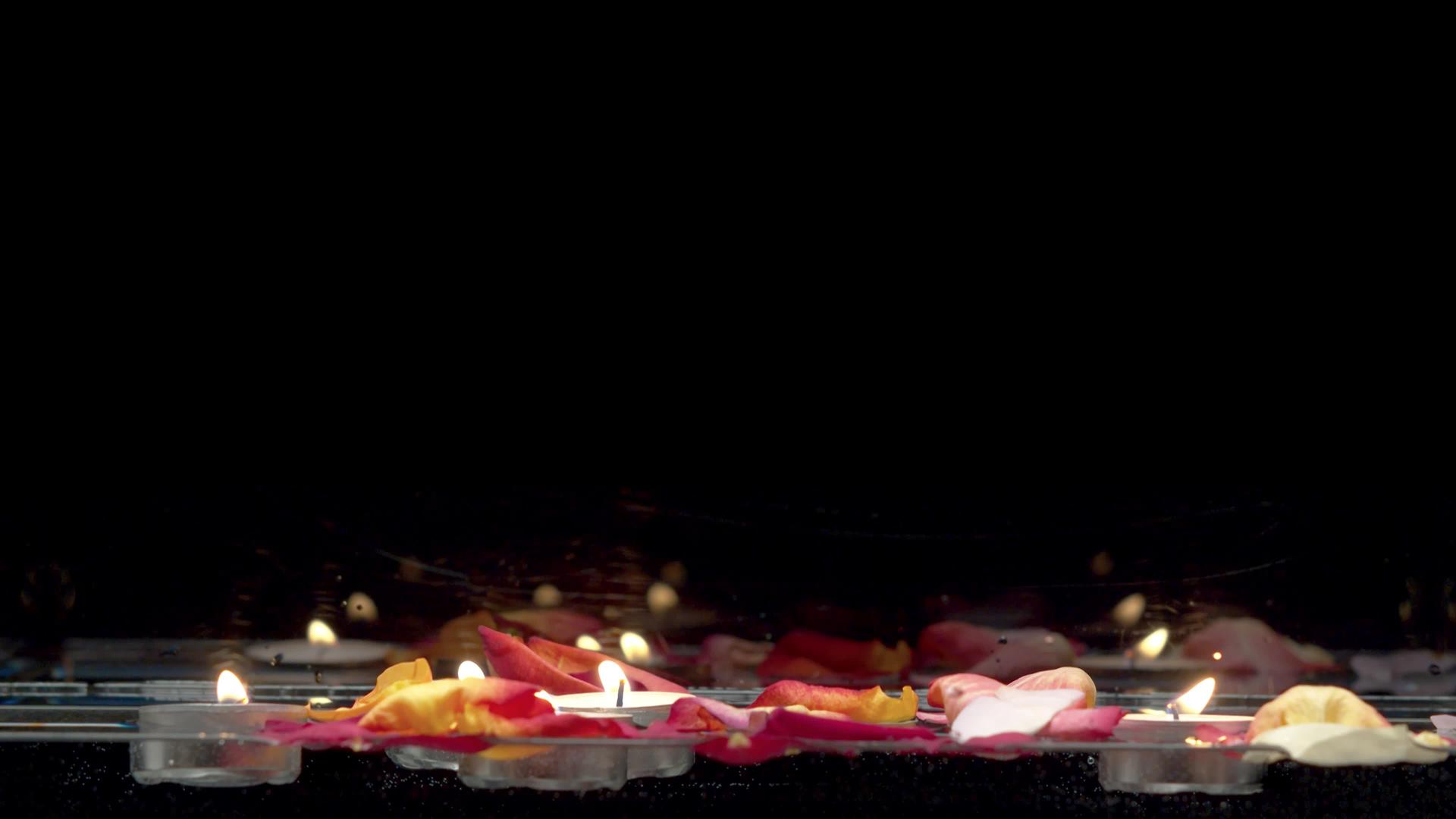 漂浮在水面和玫瑰花瓣上的蜡烛视频的预览图